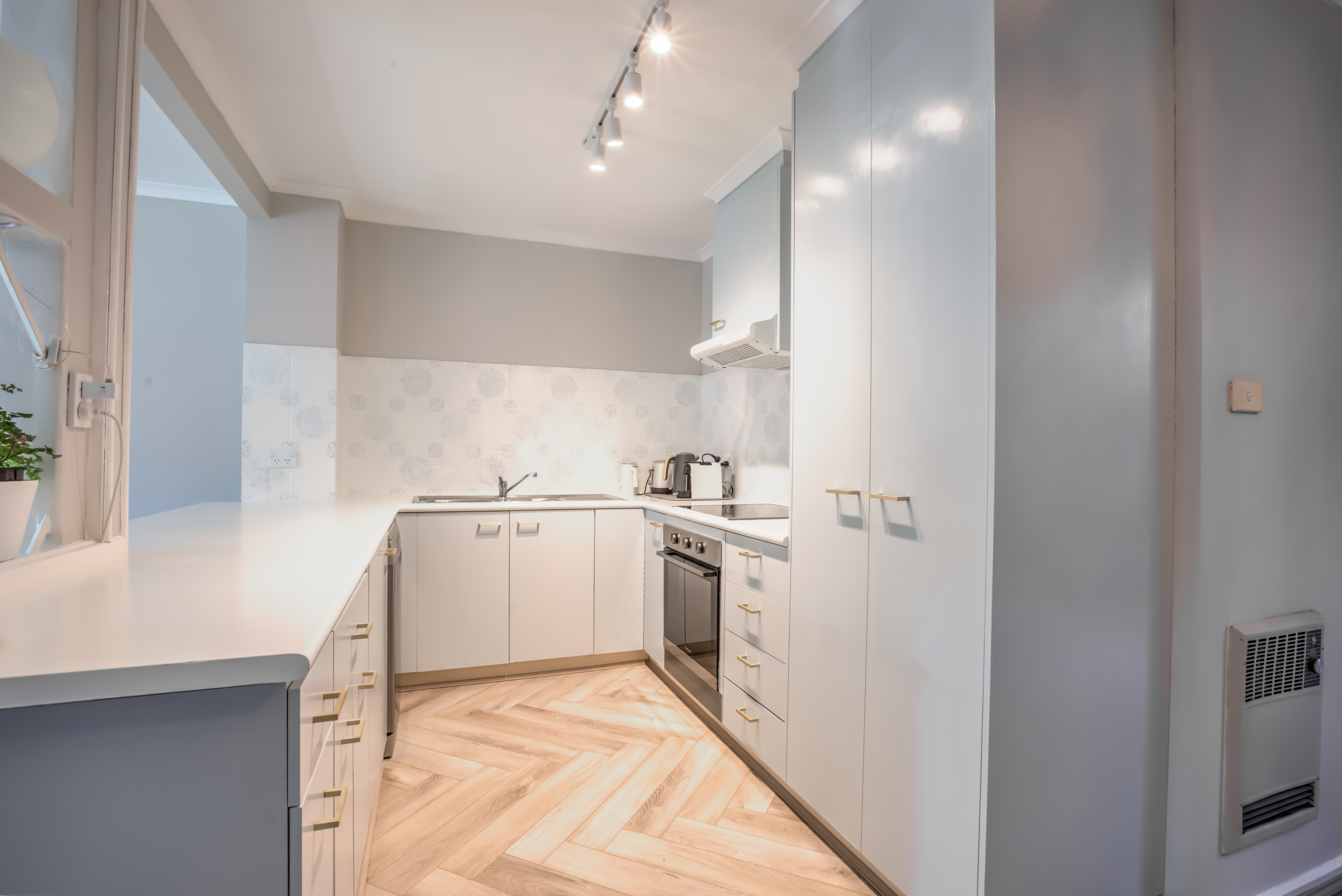 Modern white kitchen with herringbone timber floors — Canberra accommodation
