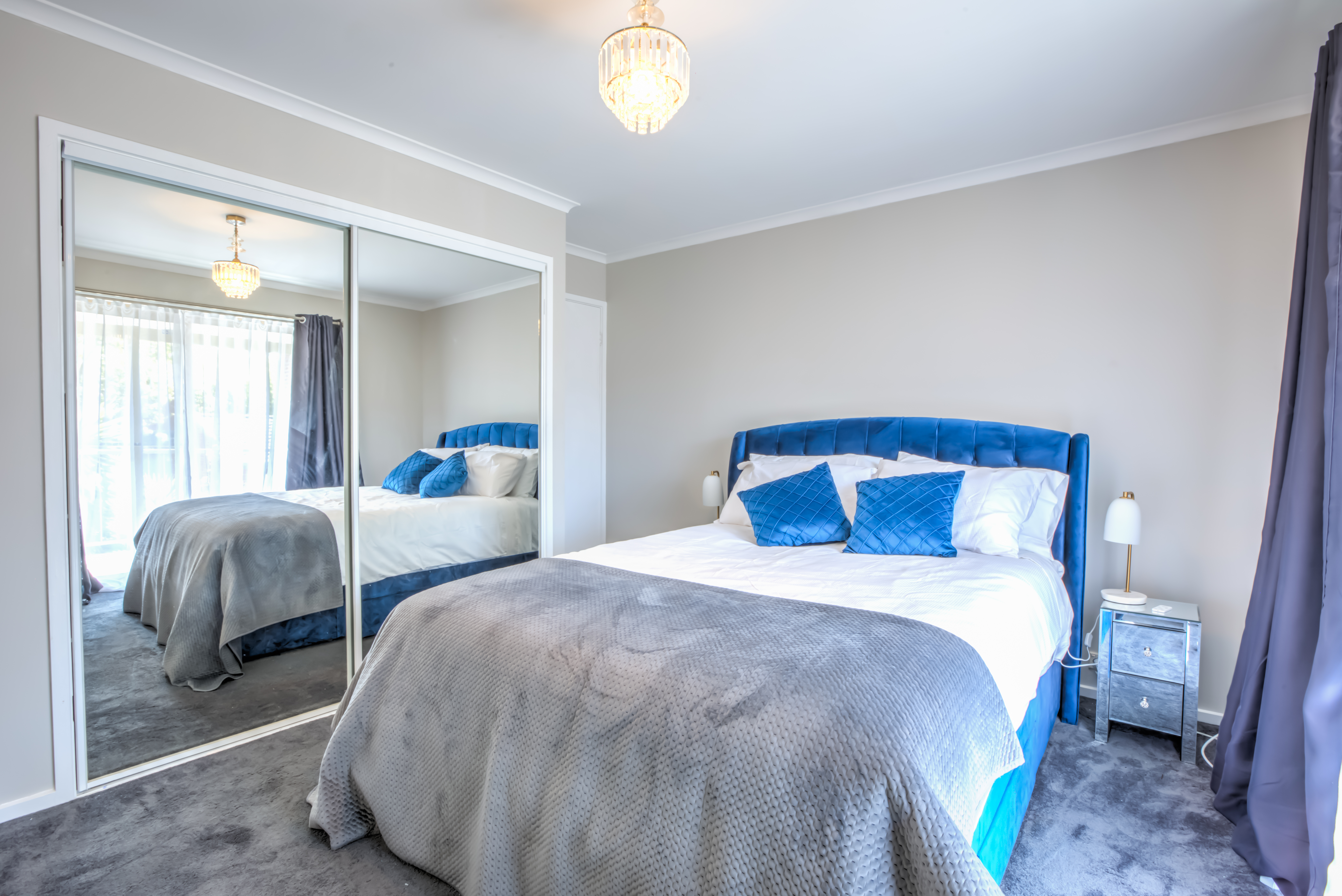 Queen-sized master bedroom with blue velvet headboard at Bijoux Townhouse near AIS