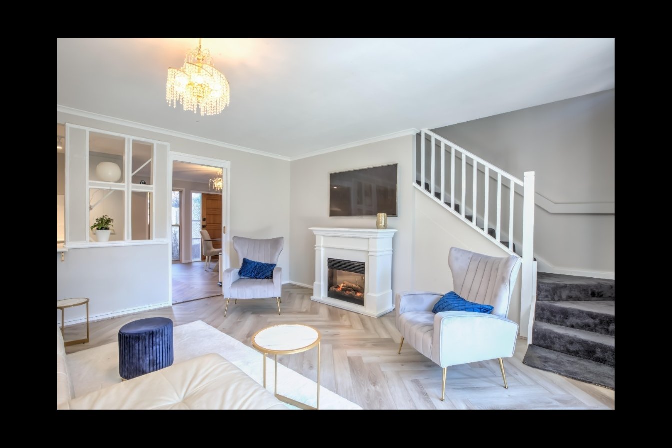 Bright open-plan living room with chandelier and fireplace — Canberra short-term rental
